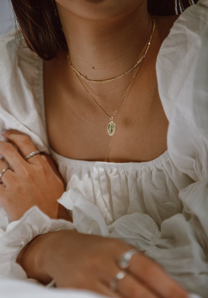 Close-up of a woman wearing a white dress and gold jewelry, showcasing elegance and style.